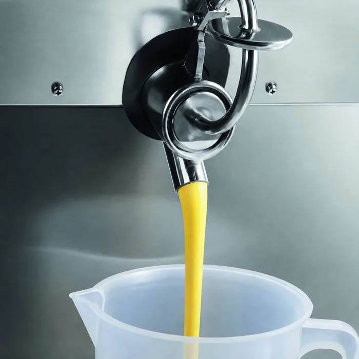Het gepasteuriseerde mengsel loopt uit de kraan van de machine in een maatbeker
